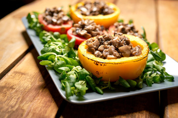 Peppers stuffed with champignons with lettuce on wooden table
