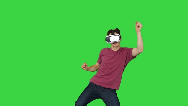 Advanced gamer in casual outfit playing dancing game in VG headset on a Green Screen, Chroma Key.