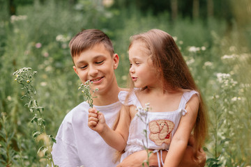 Fototapeta premium brother holds sister on shoulders outdoors in summer