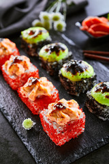 Spicy roll with masago caviar and wasabi. Sushi bar dish, restaurant menu item. Traditional eastern cuisine, national japanese cooking. Delicious asian snack, appetizer on wooden platter closeup