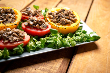 Peppers stuffed with champignons with lettuce on wooden table