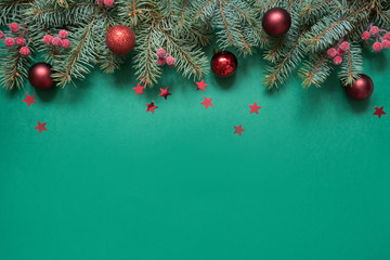 Fototapeta na wymiar Christmas tree branches, red glass balls on green with copy space. Top view. Holiday card.