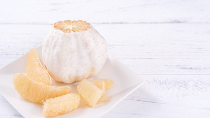 Fresh peeled pomelo, grapefruit, shaddock on bright wooden table background. Seasonal fruit for Mid-Autumn Festival, close up, copy space.