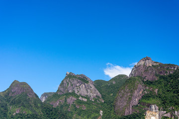 Postcard trail view where you can observe in detail de vegetation and topography of the to Serra dos Orgãos (Organs Mountain) with Finger's God highlighted in landscape.