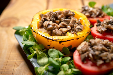 Peppers stuffed with champignons with lettuce on wooden table
