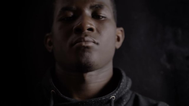 Serious angry american african young man staring at camera in the dark