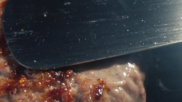 Close-up big beef cutlet is grilled, the chef presses the cutlet with an iron spatula to the grill. Slow motion video