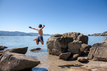 young boy jumping on the beach