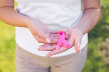 The girl holding a pink ribbon, symbol of cancer. Breast cancer awareness month.Strong woman fights cancer.