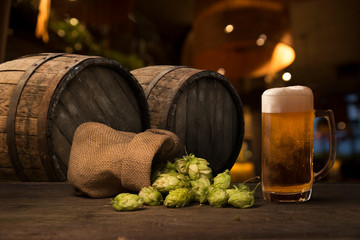 Beer brewing ingredients Hop in bag and wheat ears on wooden cracked old table. Beer brewery concept. Hop cones and wheat closeup. Sack of hops and sheaf of wheat on vintage background.
