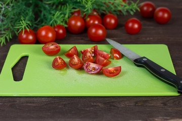 Cooking. Red Cherry Tomatoes. Chopped vegetables into pieces.