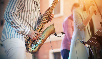 A skilled jazzman plays a Golden saxophone at a concert, creating an accompaniment to the singer.