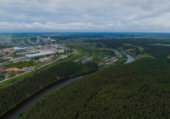 Fototapeta na wymiar Sukhoy Log city, Pyshma river, dark forest and cement factory. Russia, Aerial, cloudu day