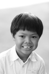 An Asian boy smiling with the first dropped-out milk tooth, black and white tone.