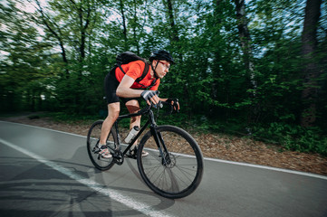 a professional cyclist in a helmet rides fast along a forest road