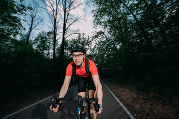 a professional cyclist in a helmet rides fast along a forest road