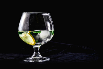 Mint cocktail with ice in a cognac glass on a black background