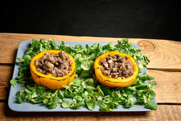 Peppers stuffed with champignons with lettuce on wooden table