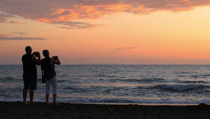 Italia, regione Toscana. Persone sulla spiaggia al tramonto