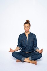 Beautyful woman in Studio in Modern Jeans outfit is sitting in a yoga seat