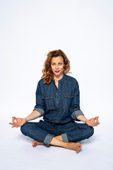Beautyful woman in Studio in Modern Jeans outfit is sitting in a yoga seat