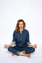 Beautyful woman in Studio in Modern Jeans outfit is sitting in a yoga seat