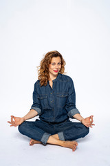Beautyful woman in Studio in Modern Jeans outfit is sitting in a yoga seat