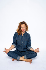 Beautyful woman in Studio in Modern Jeans outfit is sitting in a yoga seat