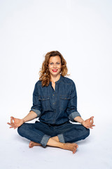 Beautyful woman in Studio in Modern Jeans outfit is sitting in a yoga seat