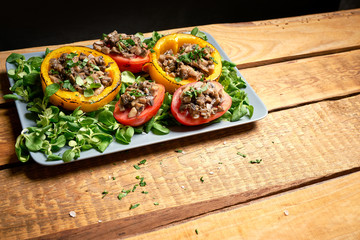 Peppers stuffed with champignons with lettuce on wooden table