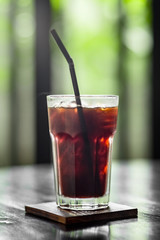 Vertical shot of glass of cold brewed coffee with a straw in it. This type of coffee made by brewing cold water with ground coffee beans.