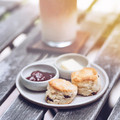 Close up shot of russian cottage cheese pancakes on a plate with jam and butter in saucers. These pancakes make a delicious dessert or a light summer meal. Iced cappuccino coffee in the background.