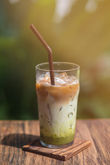 Vertical shot of iced matcha tea in a glass with straw on wooden table outdoors. No sugar. No need to brew. Selective focus