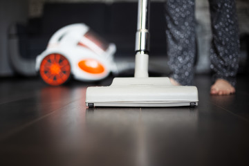 Young girl using vacuum cleaner for dark laminate.