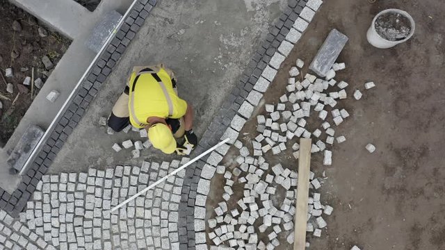 Aerial Footage of Residential Granite Brick Paving by Caucasian Construction Industry Worker.