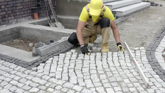 Aerial View of Caucasian Construction Contractor Paving Granite Brick Paths.