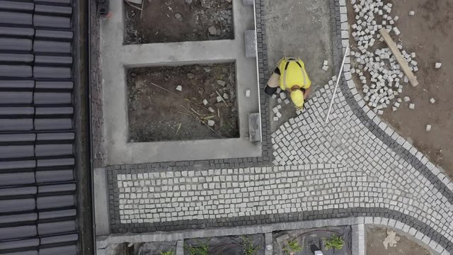 Residential Bricks Driveway Building. Caucasian Construction Worker Finishing Granite Decorative Brick Road.