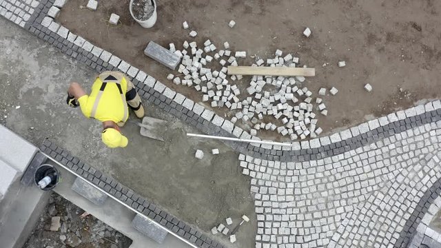 Caucasian Worker in His 30s Building Granite Paved Hardstanding Garden Path. Construction Theme