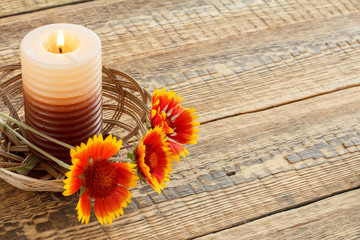 Candle and fresh flowers on wooden table.