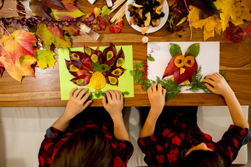 Children, applying leaves using glue, scissors, and paint, while doing arts and crafts in school.