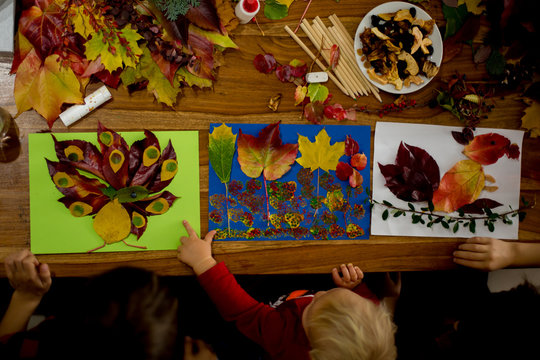 Children, applying leaves using glue, scissors, and paint, while doing arts and crafts in school.