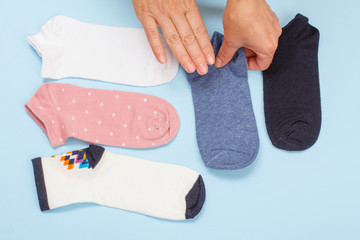 Female hands with women socks on blue background.