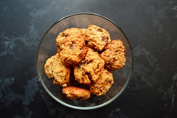 Oatmeal cookies with chocolate. Cookies on a black table background, isolated. A stack of cookies with cords.