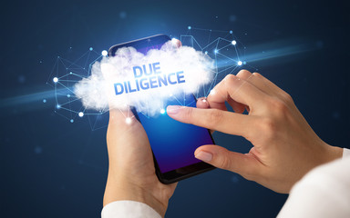 Female hand touching smartphone with DUE DILIGENCE inscription, cloud business concept