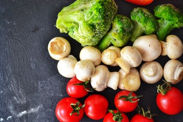 Fresh healthy vegetables. Vegetarian food. Sweet pepper, broccoli, cauliflower, mushrooms, tomato. Vegetables on a black dark background. Bright color food. Varied Food background. Place for text.