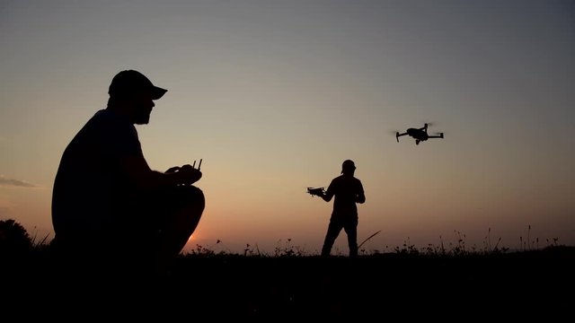 Two People with Drones Going to Recreational Flight with Their Aircrafts During Scenic Sunset. Aerial Technologies.