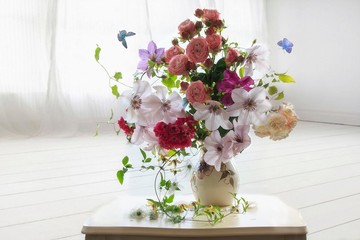 Still life with splendid bouquet of summer flowers in the white interior