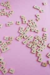 Random wooden letters on pink background