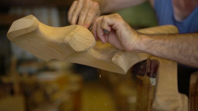 Closeup on hands of an old craftsman making a historic forcola, a wooden oarlock for gondolas, the traditional boats in Venice, Venezia. 