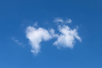 Lonely white light cloud of a fanciful shape on a blue sky background
